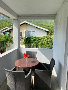 une table et des chaises sur un balcon avec un vase de fleurs dans l'établissement Apartmani Zelenika, à Herceg-Novi