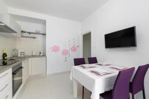a dining room with a white table and purple chairs at Jadranka in Rabac