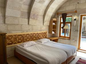 a bedroom with a large bed in a stone wall at Anatolia Raymonde Cave House in Uçhisar +30 photos