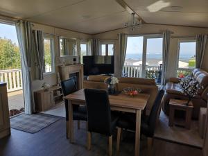 a living room with a table and a couch at Top Spec Caravan - Stunning sea views across bay in Swanage