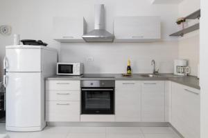 eine weiße Küche mit einem Kühlschrank und einer Mikrowelle in der Unterkunft Jadranka in Rabac