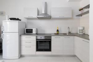a white kitchen with a refrigerator and a microwave at Jadranka in Rabac