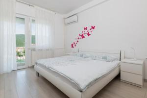 a white bedroom with a bed and a window at Jadranka in Rabac