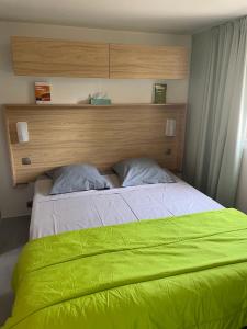 a bedroom with a bed with a green blanket at Mobil Home - Camping La Falaise in Narbonne