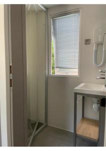La salle de bains est pourvue d'un lavabo et d'une fenêtre. dans l'établissement Mobil Home - Camping La Falaise, à Narbonne