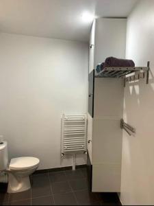 a bathroom with a toilet and a white refrigerator at Superbe studio lumineux haut de gamme tout confort in Drancy