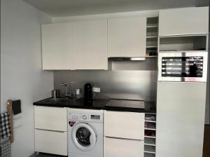 uma cozinha com armários brancos e uma máquina de lavar roupa em Superbe studio lumineux haut de gamme tout confort em Drancy