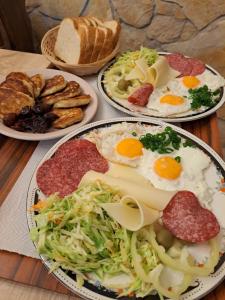 three plates of breakfast food on a wooden table at Apartmani Svitlana in Sukošan