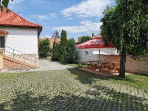 un patio con una mesa y una sombrilla roja en Glázer Szállás, en Tapolca