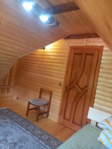 a room with a wooden door and a chair at Під горою in Volovets