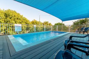 a swimming pool with a blue umbrella on a deck at Carcom Lake View in Karkom