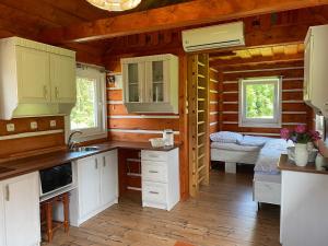 a kitchen with white cabinets and a bedroom in a log cabin at Apartmany Silver in Rokytnice nad Jizerou