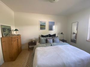 a bedroom with a white bed and a wooden cabinet at Apartment right next to the golf course and with the ocean just around the corner in Ljungskile