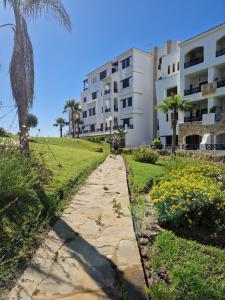 a path next to a building with palm trees and flowers at Bel appartement 3chambres Lilac's Garden Cabo Negro in Cabo Negro