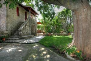 una casa de piedra con un árbol delante en Menelia Cottage, en Platístoma