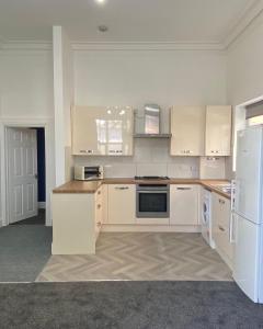 an empty kitchen with white cabinets and a refrigerator at Lovely 1 bed ground floor flat in Leamington Spa in Leamington Spa