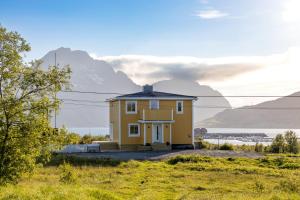 una casa gialla su una collina con montagne sullo sfondo di PederStua a Storeidet