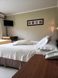 1 dormitorio con 1 cama y mesa con ordenador portátil en Marvic Hotel en San Pedro