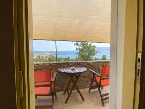 een tafel en stoelen op een balkon met uitzicht op de oceaan bij Archipelagos Boutique Hotel in Skhoinoussa