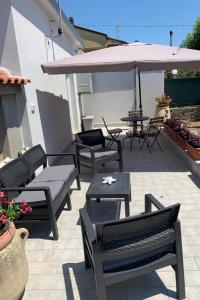 een patio met stoelen en tafels en een parasol bij Appartamenti Mamma Marisa in Minturno