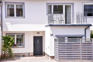 Biały dom z czarnymi drzwiami i balkonem w obiekcie Apartamenty Turystyczna 25 w Kudowie Zdroju