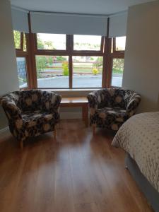um quarto com 2 cadeiras, uma cama e uma janela em Beechwood Lodge em Blarney