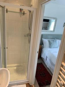 a bathroom with a shower next to a bed and a sink at Parsnips House BnB Glastonbury in Glastonbury