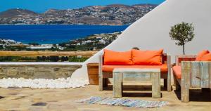a patio with an orange couch and a table at Villa Mira Paros - Luxury Suites in Kampos Paros