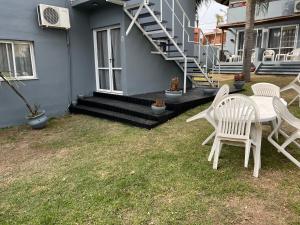 a patio with white chairs and a table in front of a house at Costadorada in Villa Carlos Paz