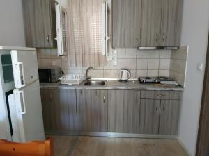 eine Küche mit Holzschränken und einem weißen Kühlschrank in der Unterkunft Milto's Studios in Parga