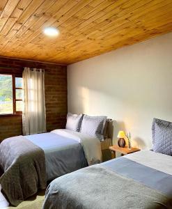 a bedroom with two beds and a wooden ceiling at Villagio Angatu in Santo Antônio do Pinhal