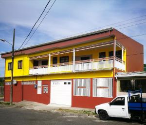 un edificio con un coche blanco aparcado delante de él en Aptos Casa Caribe, habitaciones privadas en aptos compartidos & aptos completos con auto entrada, en Puerto Limón