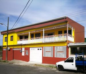 a building with a white car parked in front of it at Aptos Casa Caribe, habitaciones privadas en aptos compartidos & aptos completos con auto entrada in Puerto Limón