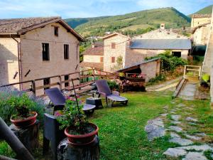 a garden with chairs and a table and a building at Maison en Pierre in Fiastra