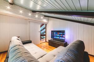 a living room with a white couch and a television at Villa Bog - Villa con piscina e campo da tennis in Piegaro