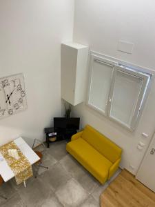 uma sala de estar com um sofá amarelo e uma janela em Silvano Cozy Loft em Bolonha