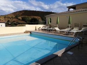 a large swimming pool with chairs and umbrellas at Casa Giulia in San Teodoro