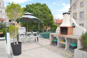 eine Terrasse mit einem Tisch, Stühlen und einem Sonnenschirm in der Unterkunft Alfama Lisbon Studio in Lissabon