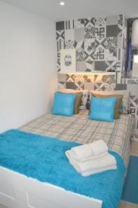 a large bed with blue pillows and towels on it at Alfama Lisbon Studio in Lisbon
