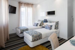 リスボンにあるMarino Lisboa Boutique Guest Houseのベッド2台とソファが備わるホテルルームです。