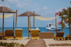 eine Gruppe von Stühlen und Sonnenschirmen am Strand in der Unterkunft Elektra Comfort Hotel in Skala Prinos