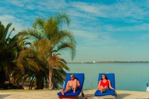 Ein Mann und eine Frau sitzen auf Stühlen am Strand in der Unterkunft Marina del Faro Resort in Termas de Río Hondo