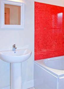 a white bathroom with a sink and a red wall at Hillview House Hostel Inverness in Inverness