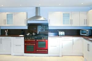 cocina con fogones rojos y armarios blancos en Hillview House Hostel Inverness, en Inverness