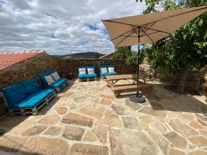 a patio with two chairs and an umbrella at Casa das Indrineiras in Mogadouro