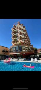 un edificio con persone in acqua di fronte a una piscina di Hotel Flamingo a Gatteo a Mare