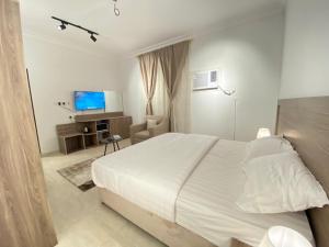 una camera da letto con un grande letto bianco e una televisione di نايتس للوحدات المفروشة a Tabuk