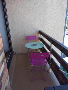 2 chaises violettes et une table sur un balcon dans l'établissement Le petit Cabourgeais, à Cabourg