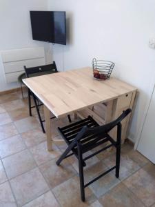 mesa de madera con silla y TV en Le petit Cabourgeais, en Cabourg