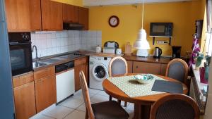 a kitchen with a table and a kitchen with a washing machine at Ferienwohnung in Gartenlandschaft in Kassel